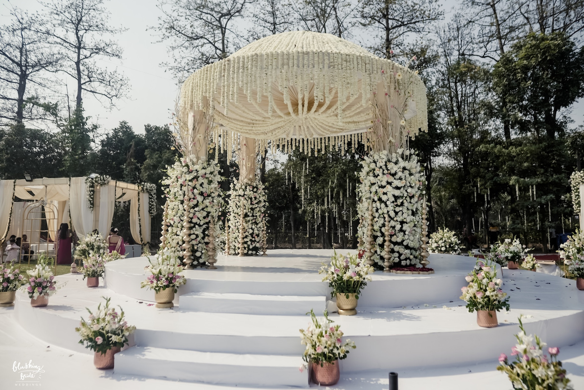 Mandap dressed in white florals under open sky