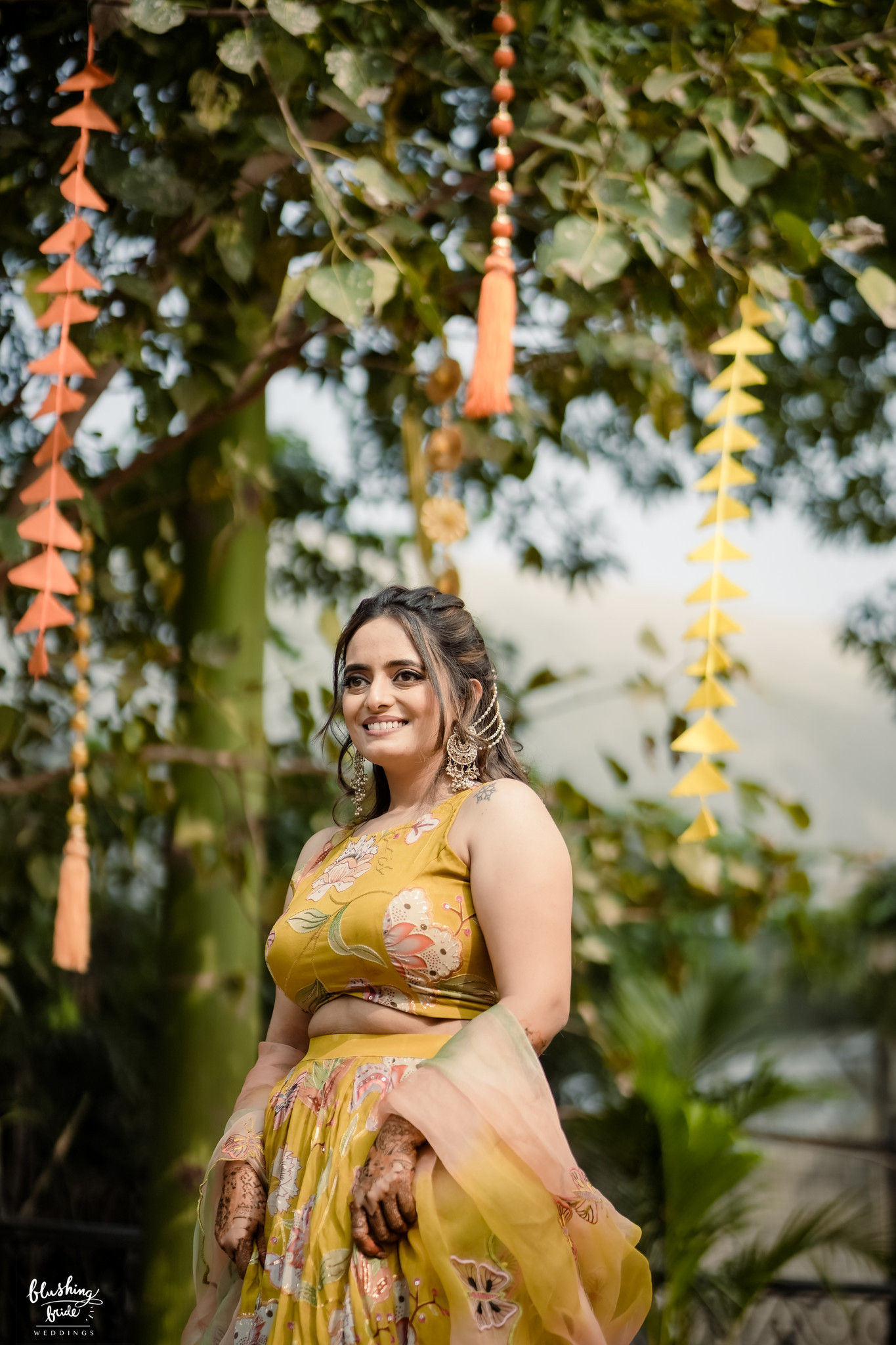 Bride in yellow beneath hanging floral strands
