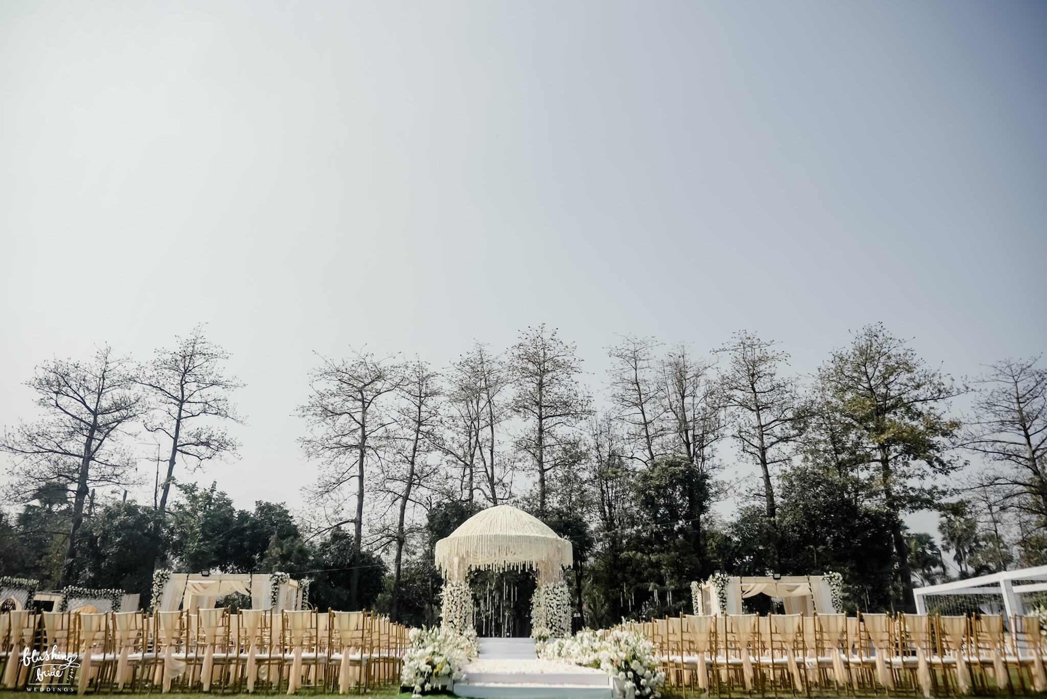 Mandap on a lawn framed by bare trees