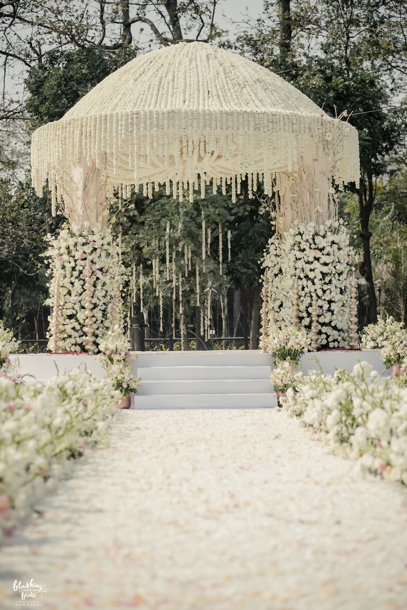 Mandap at the end of a petal-strewn aisle